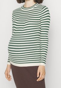Maglione a righe in verde e crema in tessuto a coste, con maniche lunghe e scollatura rotonda, indossato sopra una gonna a coste marrone.