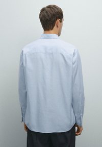 Hellblau gestreiftes Hemd mit langen Ärmeln, Knopfkragen und abgerundetem Saum. Aus glattem Stoff mit lässiger Passform gefertigt.