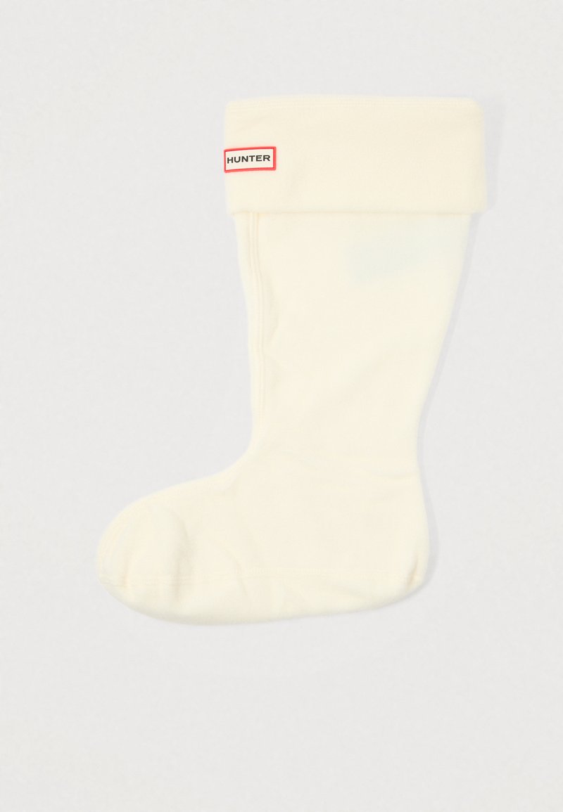 Pánské vysoké ponožky do kozaček v krémové barvě, vyrobené z měkkého materiálu. Obsahují přehnutý lem s červenou a bílou značkovou etiketou. Hladká textura.