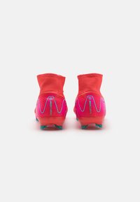 Football boots with a high collar, vibrant red and pink colorway, textured finish, and teal sole with cleats for traction.