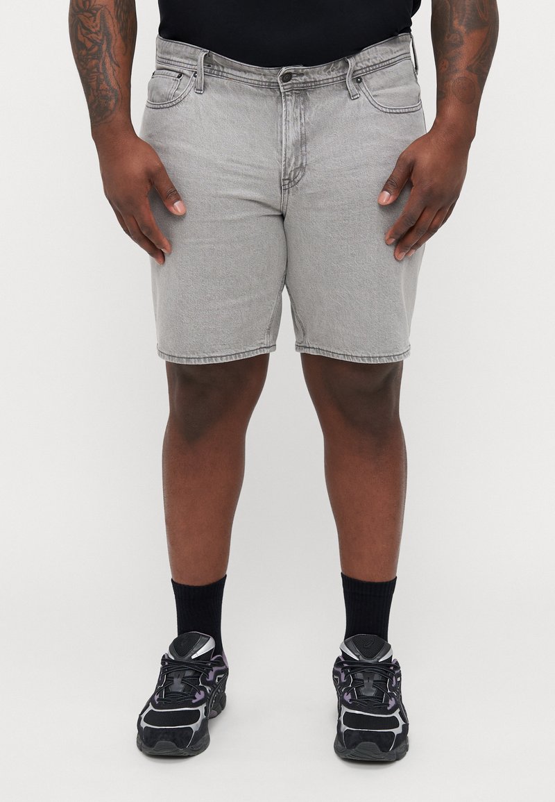 Grijze denim shorts met een normale pasvorm, voorzakken en een knoopsluiting, gecombineerd met zwarte sportschoenen en zwarte sokken.