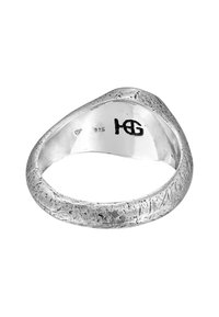 Silverring med en strukturerad yta, med en slät inre band. Märkt med "925" för sterling silver och en initialer-logotyp.