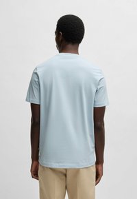 Light blue short-sleeve T-shirt with a round neckline. Smooth texture, regular fit, and subtle stitching detail along the shoulders and hem.