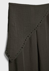 Jupe en tissu gris foncé avec un design portefeuille asymétrique et de petits détails découpés en cercle le long du bord.