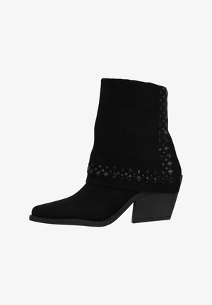 Botas de tobillo de ante negro con punta afilada, detalles decorativos de tachuelas en el puño y un diseño de tacón grueso.