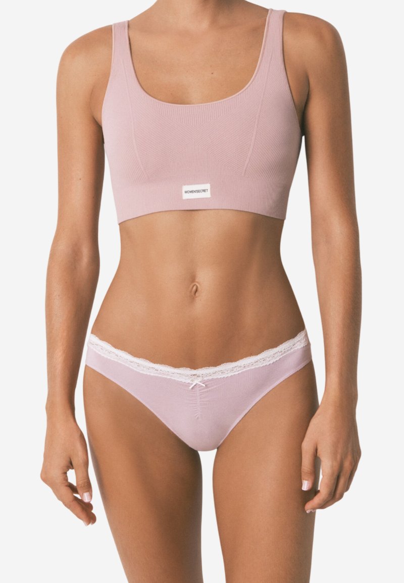 Reggiseno rosa chiaro con texture a coste e spalline larghe, abbinato a mutandine coordinate con bordino in pizzo e un dettaglio a fiocco davanti.