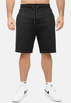 Pantaloni shorts neri in jersey con cintura elastica e cordino, di lunghezza al ginocchio, caratterizzati da una texture liscia e orli rifiniti.