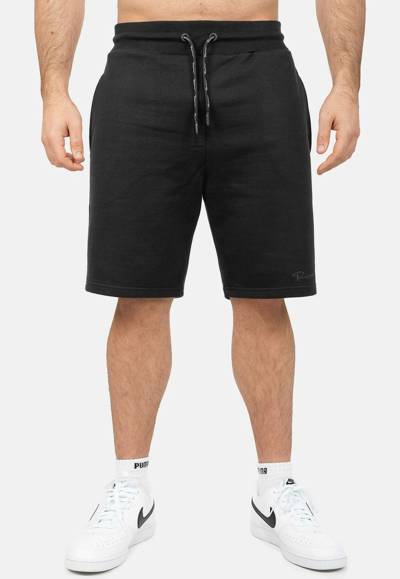 Pantaloni shorts neri in jersey con cintura elastica e cordino, di lunghezza al ginocchio, caratterizzati da una texture liscia e orli rifiniti.