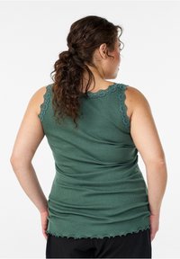 Grünes geripptes Tanktop mit gezacktem Spitzenbesatz am Ausschnitt und an den Armlöchern. Strukturierter Stoff mit figurbetonter Silhouette und leicht gerafftem Saum.