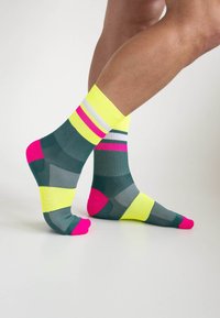 Bunte Knöchelsocken in Grün mit pinken, gelben und grauen geometrischen Mustern; verfügen über verstärkte Fersen- und Zehenakzente für zusätzliche Haltbarkeit.
