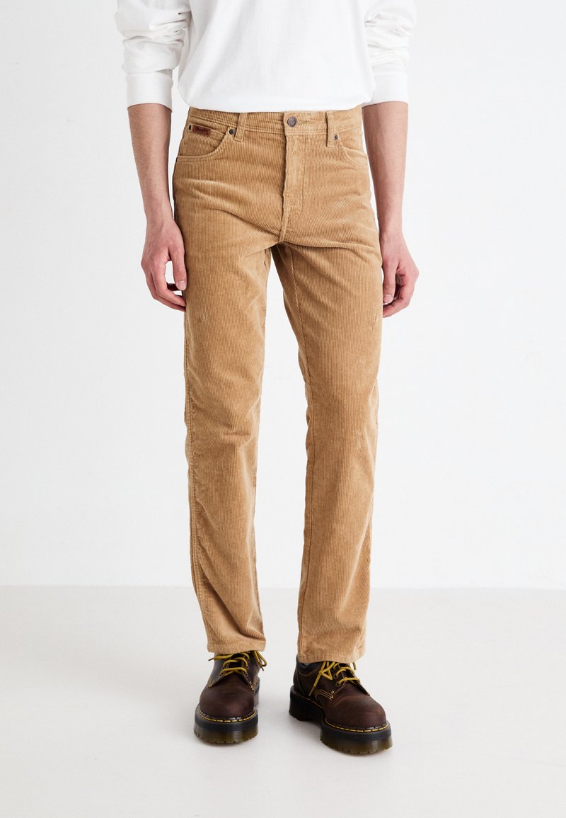 Pantalons en velours côtelé marron clair avec une coupe droite, dotés de poches avant, d'une fermeture à bouton et d'une texture à côtes verticales discrètes.