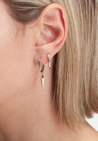 Silberne Creolen mit einem spitz zulaufenden Tropfenanhänger. Das Design ist elegant, mit einer polierten Oberfläche und einem schlichten, modernen Look.