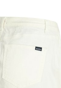 Jean en denim blanc au design classique. Comprend une poche arrière unique avec une étiquette noire "SEASIDE". Texture lisse et couture standard.