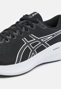 Black athletic shoe with a textured upper, white accents, and a gel cushioning sole. Features a lace-up design with breathable mesh areas.