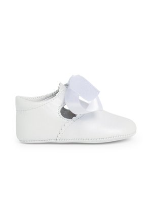 Zapato de cuero blanco con bordes ondulados, que presenta un lazo ancho de cinta blanca en la parte delantera. Punta redondeada y costura elástica en los laterales para un mejor ajuste.
