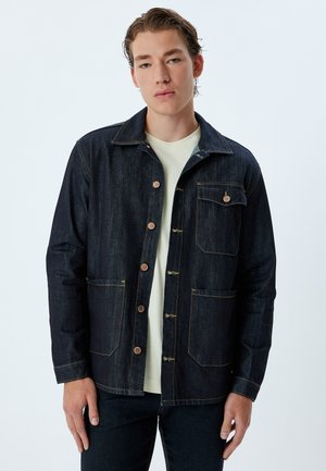 Dark denim jacket with a button-up front, two chest pockets, and contrasting yellow stitching. Features a collar and a relaxed fit.