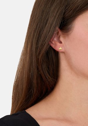 Goldene Steckerohrringe in zartem Blattdesign, mit glatter Textur und minimalistischem Stil, getragen am Ohr eines Modells.