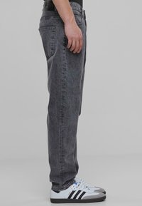 Jeans din denim gri cu un croi drept, design cu cinci buzunare și ușoară decolorare. Asortați cu încălțăminte sport alb-negru.