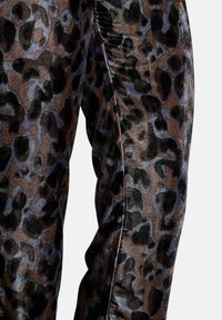 Pantaloni stampa leopardata in tessuto morbido e strutturato nei colori marrone e nero, con finitura lucida e design aderente.