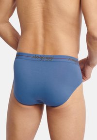 Blaue Herrenunterwäsche aus einem glatten Material mit einem kontrastierenden Schwarz-Rot elastischen Bund, der mit "sloggi"-Branding versehen ist.