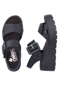 Sandales noires avec une semelle texturée, des larges sangles et une boucle sur le côté. Fabriquées en matériaux synthétiques avec une semelle intérieure rembourrée pour le confort.