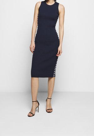 Marineblauw geribde midi-jurk met mouwloos ontwerp, voorzien van een zijdelingse vetersluiting. Gladde textuur en aansluitende silhoeet. Hoog splitaccent.