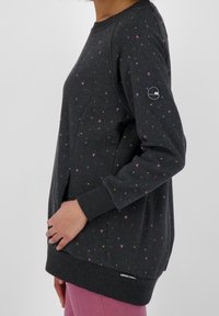 Sudadera gris oscuro con patrones de triángulos multicolores, puños acanalados y dobladillo redondeado. Incluye logo en la manga izquierda.
