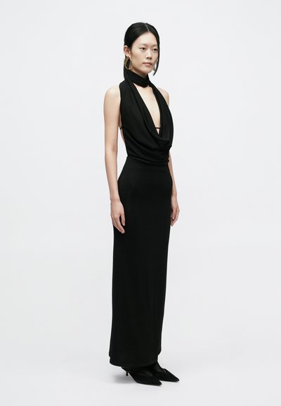 Μαύρο, αμάνικο φόρεμα με βαθύ ντεκολτέ σε σχήμα V, λαιμόκοψη τύπου drapé και εφαρμοστή γραμμή. Διαθέτει πλαϊνές ανοίγματα και φτάνει μέχρι τον αστράγαλο.