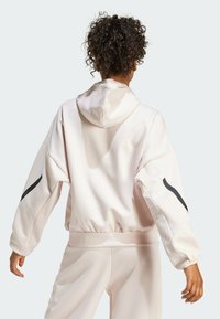 Light pink hooded sweatshirt with a relaxed fit, elastic waistband, and black accent stripes on sleeves. Smooth texture and spacious design.