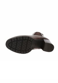 La semelle de la botte en cuir marron présente un fond en caoutchouc texturé avec un motif de crantage. Un talon bloc et un matériau lisse complètent le design.