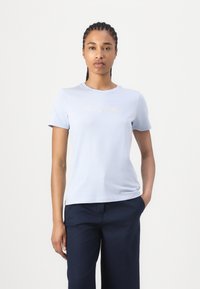 Šviesiai mėlynas medvilninis marškinėliai su trumpomis rankovėmis, ant krūtinės su auksiniu siuvinėtu "Tommy Hilfiger" logotipu. Lygus paviršius.