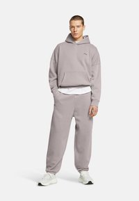 Ljusgrå sweatshirt med huva, med en framficka, i kombination med matchande sweatpants. Texturerad tyg med elastiska muddar och midjeband.