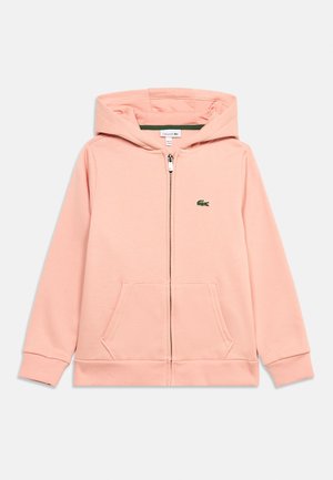 Sweat à capuche zippé rose clair avec poches avant, poignets côtelés et petit logo crocodile vert sur le côté gauche de la poitrine.