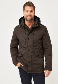 Braune wasserdichte Jacke mit großer Kapuze, Reißverschlusstaschen auf der Brust und geknöpftem Frontverschluss. Verfügt über eine strukturierte Oberfläche und Seitentaschen.