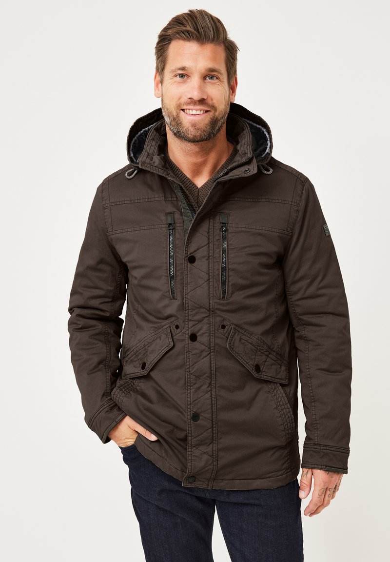 Braune wasserdichte Jacke mit großer Kapuze, Reißverschlusstaschen auf der Brust und geknöpftem Frontverschluss. Verfügt über eine strukturierte Oberfläche und Seitentaschen.