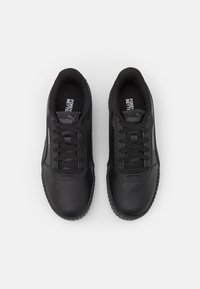 Zapatillas deportivas negras con un exterior de cuero suave, ligero acolchado y suelas de goma texturizada. Presentan cordones negros y una marca en la lengüeta.