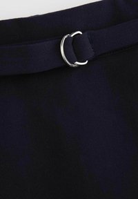 Granatowy pasek materiałowy z srebrną klamrą typu D-ring, o gładkiej fakturze i płaskim kształcie, zabezpieczony pętlą na jednym końcu.