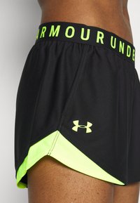 Svarta sportshorts med en neongrön midja och dekorationer. Har elastisk linning, sidoklippdesign och Under Armour-logga.