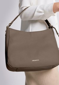 Bolso de mano de cuero marrón con superficie texturizada, que cuenta con una correa corta y un logo dorado, que combina a la perfección funcionalidad y diseño moderno.