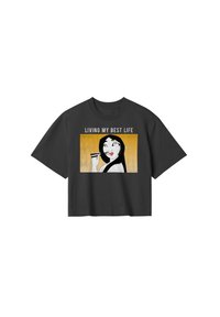 Czarny skrócony t-shirt z graficznym wzorem przedstawiającym kobietę trzymającą pałeczki, z napisem "ŻYJĘ NAJWYŻEJ LEPIEJ" i żółtym tłem.