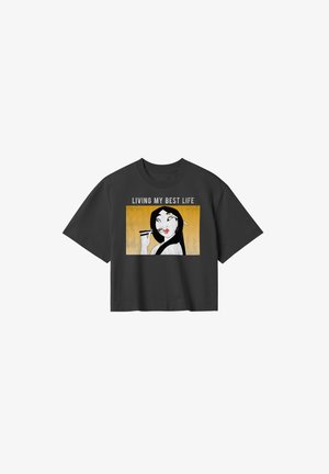T-shirt cropped nero con un design grafico raffigurante una donna che tiene delle bacchette, testo "VIVENDO LA MIA MIGLIORE VITA" e uno sfondo giallo.