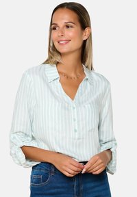 Camicia button-up teal chiaro con strisce verticali bianche, maniche ripiegate, due tasche frontali e colletto. Tessuto morbido con una texture liscia.