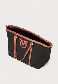 Črna torba iz teksturiranega materiala z rjavimi sintetičnimi usnjenimi detajli, z dvema naramnicama in dekorativnim logotipom na sprednji strani.