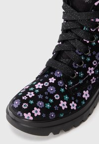 Stivale nero con lacci e suola spessa, decorato con piccoli motivi floreali rosa, viola e verdi su tutta la superficie.