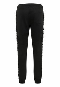 Schwarze Sweatpants aus Baumwolle mit schmalem Bein-Design, elastischem Bund und weißem Branding an der Seite. Ein einzelnes Gesäßtasche.