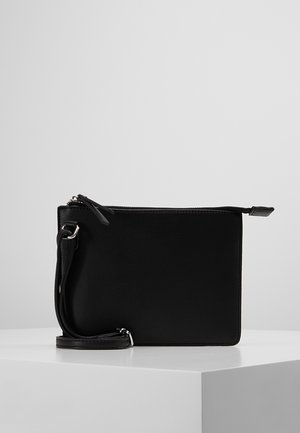 Sort læder crossbody taske med lynlås, justerbar rem og sølvhardware, vist på en hvid piedestal.