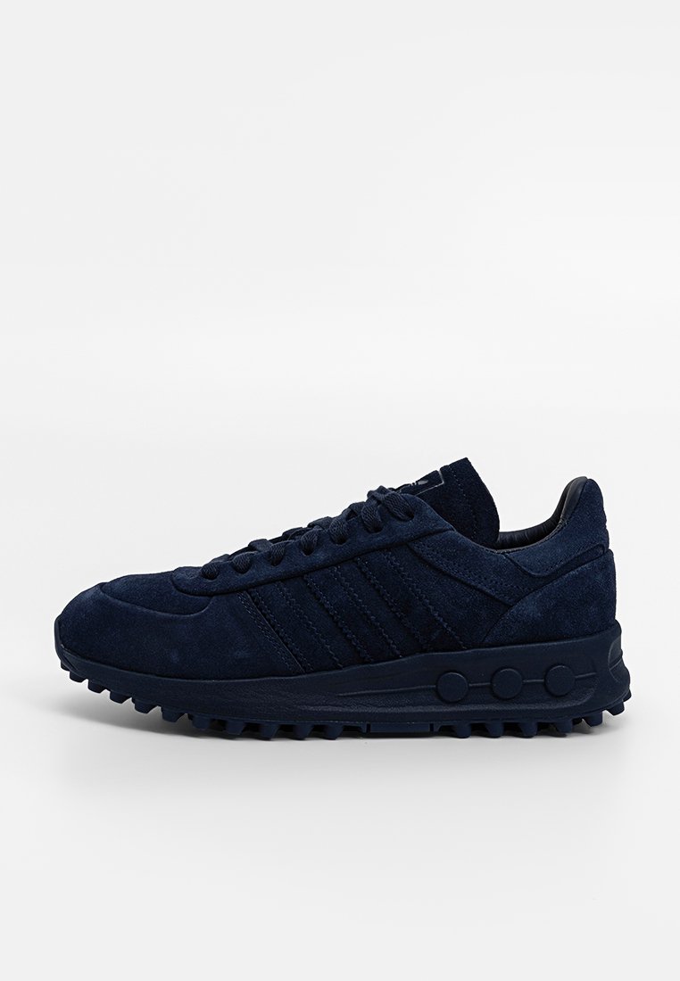 Sneaker en daim bleu foncé avec fermeture à lacets, semelle texturée et trois bandes sur le côté, présenté en profil latéral sur un fond blanc.