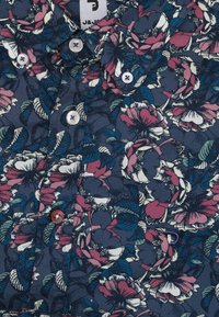 Bloemig shirt met korte mouwen, met een donkerblauwe achtergrond en witte en roze botanische patronen. Vier witte knopen en een kraagdetail.