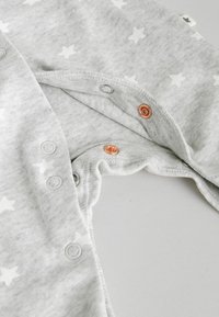 Grauer Baumwoll-Strampler mit weißem Sternmuster, ausgestattet mit Druckknöpfen aus Metall in Silber und Roségold. Weiche Textur, abgerundeter Ausschnitt.