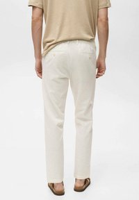 Light beige, pinstriped trousers with a straight cut, featuring two back pockets and a subtle texture. Paired with brown sandals.